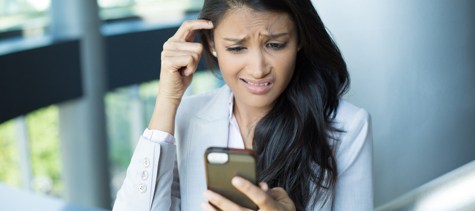 Closeup portrait, smart pretty young female in gray white suit, dumbfounded flabbergasted by what she sees on cell phone, isolated indoors office background